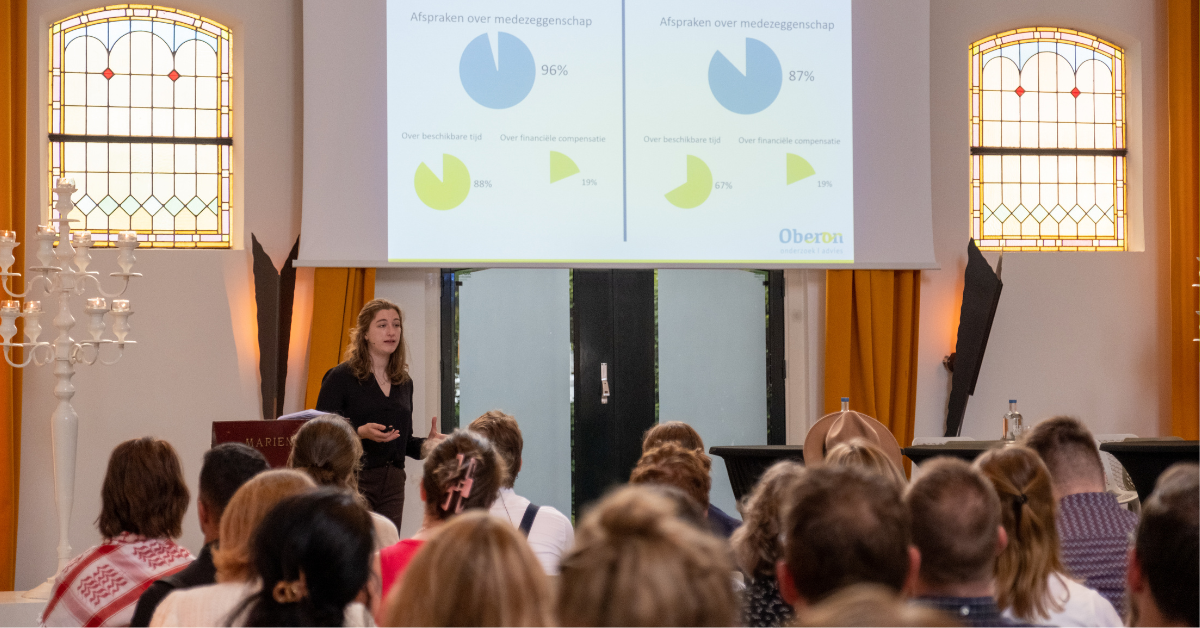 Onderzoeker-adviseur Maren Vleeskens presenteert namens Oberon de uitkomsten van de Monitor Medezeggenschap Hogescholen en Universiteiten 2024 op de Dag van de Medezeggenschap.
